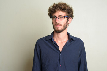 Face of young bearded businessman with eyeglasses thinking