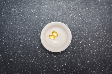 gelatin capsules with vitamin D in a pill box, top view.