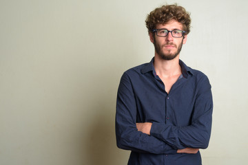 Fototapeta premium Young bearded businessman wearing eyeglasses with arms crossed