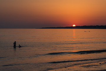 un coucher de soleil romantique sur la mer. Des baigneurs le soir. Des personnes se baignant avec un coucher de soleil. des gens nageant au coucher de soleil. Destination de rêve