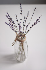 transparent vase in Scandinavian style with dried flowers purple on a light background vertical photo