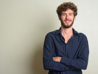 Obraz premium Happy young bearded businessman with curly hair smiling with arms crossed