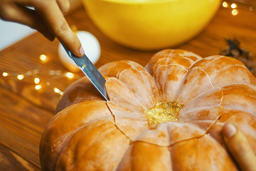 Process hands cutting with knife character face on pumpkin object preparation to halloween holiday.
