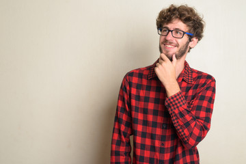 Fototapeta premium Happy young bearded hipster man with curly hair thinking