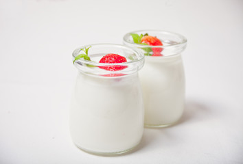 Two portions natural homemade yogurt in a glass jar with fresh strawberry