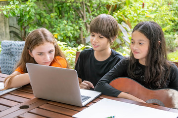 Children, boy and girl, using laptop computer for online learning in garden at home