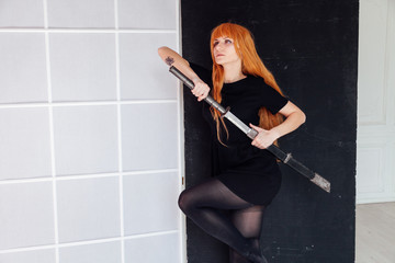 Woman cosplayer anime with red hair holds a Japanese sword