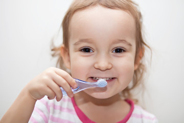 Little cute girl smailing and brushing her teeth.