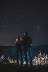 Couple, man and woman look at the sky full of stars, romantic atmosphere. travel. peak, vertical photo