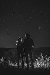 Couple, man and woman look at the sky full of stars, romantic atmosphere. travel. peak, vertical photo, black and white