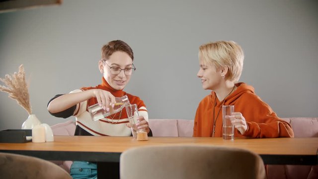 Girl in glasses is pouring water into a glass