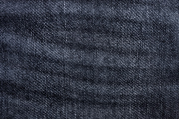 Rumpled dark gray or black jeans texture as background. Top view