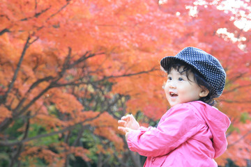 Little girl laughs that surrounded by autumn leaves