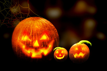 Halloween background. Jack o lanterns glowing in the dark on defocused background with spider web.