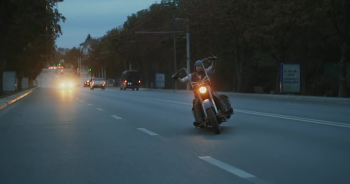 Biker moving fast and leaning his chopper motorcycle while riding on a road, showing dangerous riding skills. Increasing leaning angle till carving a sparks by touching asphalt with metal floorboards