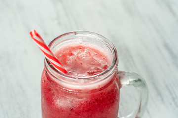 Fresh organic red smoothie in glass mug on white table, close up. Refreshing summer fruit drink. The concept of healthy eating. Cranberry and raspberry smoothie