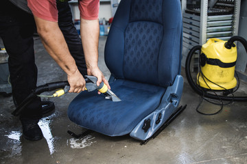 An auto service worker prepares and cleans the car seat