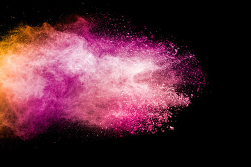 Abstract pink and orange powder explosion on  black background. Freeze motion of pink orange dust splashing.