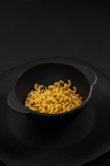 pasta in a black bowl, black plate. black background