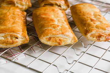 Savory cheese and onion puff pastry rolls fresh out of the oven cooling on a cooking trivet a vegetarian alternative to the usual sausage roll