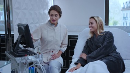 At beauty salon young woman consulting with cosmetologist examining body and face health condition before spa procedure. Cosmetology concept.