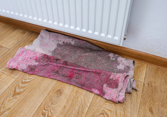 Wet rag in a pool of water under the radiator heating. Defective leaking heater flooded the floor...