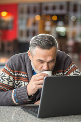 Man sitting in a cafe working with laptop