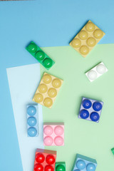 Toy bricks on three colored background. Children constructor. Flat lay / Top view