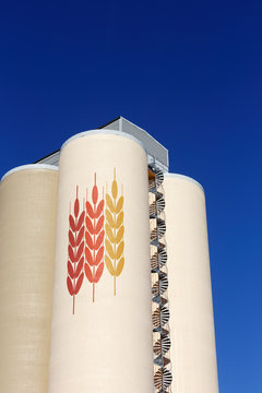 Sodertalje, Sweden - March 11, 2017: A sand-colored concrete silo  in service for Lantmannen used  for storage of grain with three wheat axs painted on the upper part and with a spiral staircase.