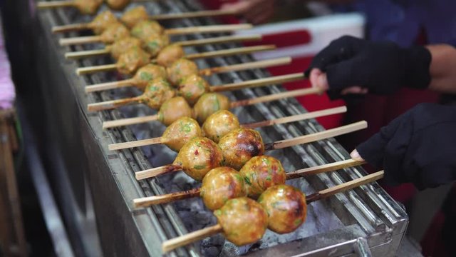 Vendor cooking spicy Jang Lon on charcoal grill machine. Traditional Thai street food for sale in Floating Market. Thailand. footage video 4k.