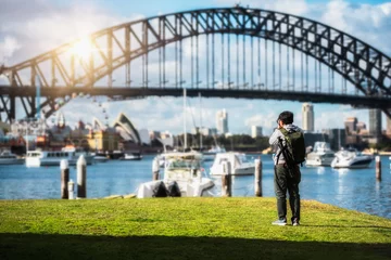 Photo sur Plexiglas Sydney Harbour Bridge Traveller man young backpacker standing and using a professional Mirrorless DSLR camera take photo beautiful of Sydney city skyline with Sydney harbour bridge north shore in Australia.