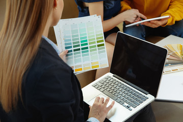 Interior designer working with young couple. Lovely family and professional designer or architector discussing conept of future interior, working with colour palette, room drawings in modern office.