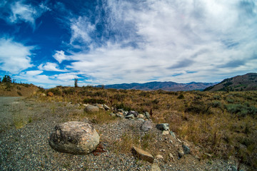 Cascade Mountain Range in Washington State's Okanogan-Wenatchee National Forest with boulders, a hilltop road, and cloud-full blue sky