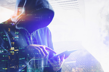 Unrecognizable hacker with tablet in city