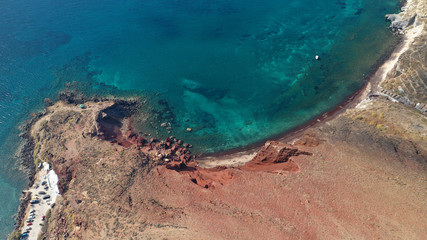 Obraz premium Aerial drone photo of iconic famous red rocky volcanic beach with deep turquoise sea visited by sail boats, Santorini island, Cyclades, Greece
