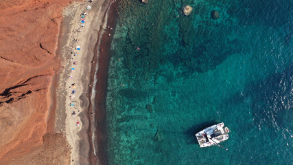 Aerial drone photo of iconic famous red rocky volcanic beach with deep turquoise sea visited by sail boats, Santorini island, Cyclades, Greece