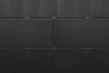 Black uneven surface of building wall with bracketed tiles