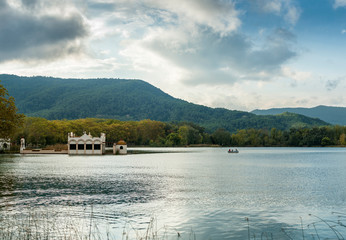 Fototapeta premium A pleasure rowing boat sails along Lake Banyoles in Girona (Spain) in front of the building of a fishermen's guild. 