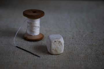 Fototapeta na wymiar spool of white thread and a needle on a towel