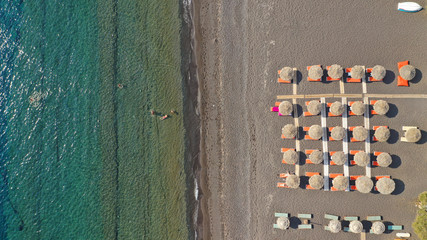 Aerial drone top down photo of famous organised with umbrellas and sunbeds black sand beach and bay...