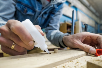 Carpenter using glue to connect parts of wooden timbers. - obrazy, fototapety, plakaty