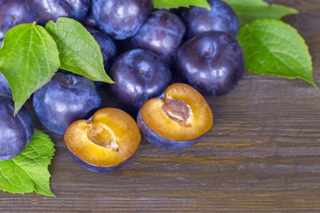 Fototapeta premium ripe plums and green leaves close-up. pile of ripe blue plums closeup. background with ripe plums.