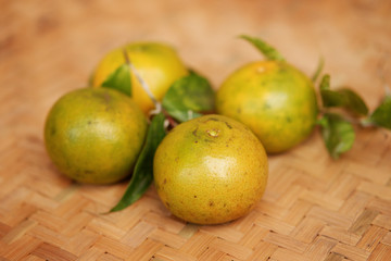 Fresh oranges on the surface of traditional bamboo rattan wicker tray.