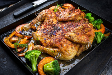 Barbecue spatchcocked chicken al mattone chili with pumpkin and broccoli as closeup on an old metal tray