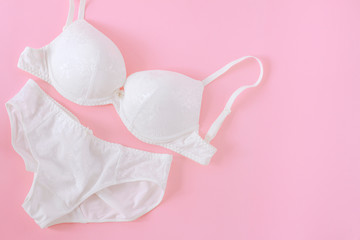 Set of white underwear on a pink background. Beautiful bra and panties top view
