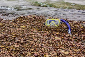 snorkeling glasses and tube on crushed stones beach waterfront outdoor environment life style photography with empty copy space for your text 