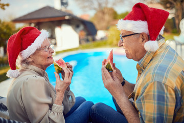 senior couple on christmas in Santa hats eating watermelon
