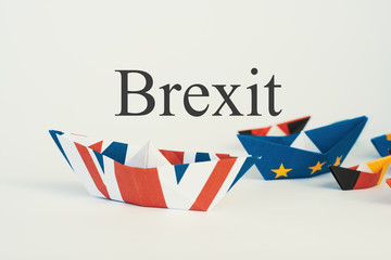Obraz premium Brexit UK EU concept - paper ships from the flags of the European Union and the UK on a blue background