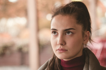 Brunette girl in a sweater in a cafe on the street in the autumn in a pensive mood.