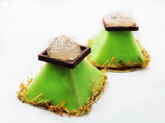 Lime pyramid dessert with aloe vera jelly and flower petals on white background